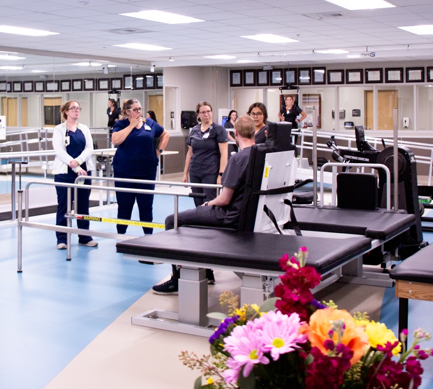 Photo of staff demonstrating high-tech treatment bed with lifting mechanisms and detachable hand rails