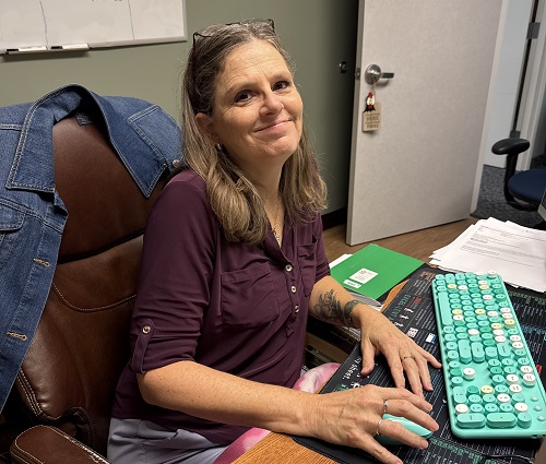 Color photo of Erika Johnson sitting at her desk