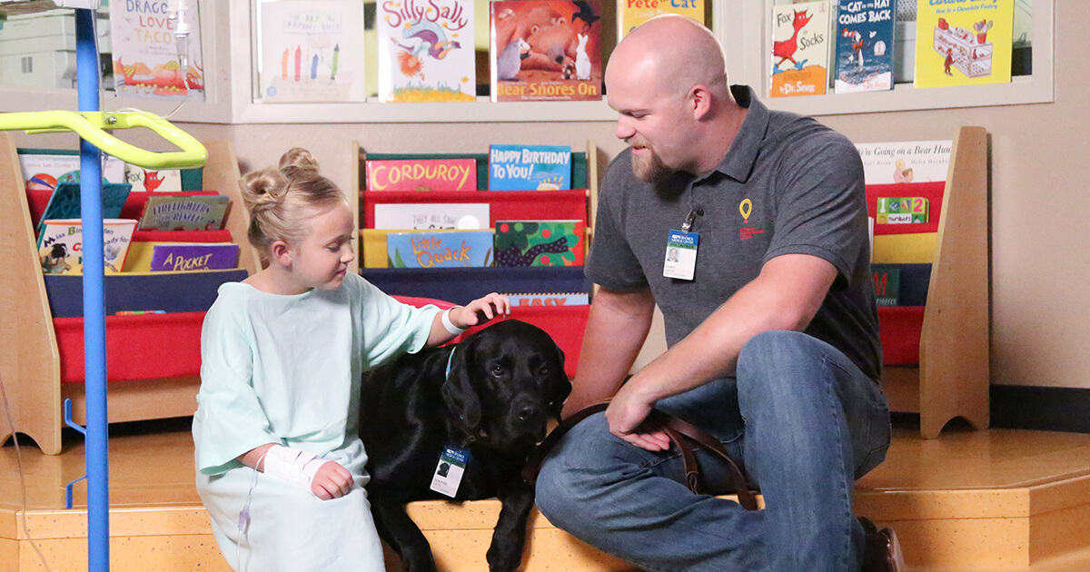 little girl petting black lab 