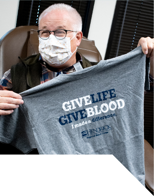 Dr. Wiley holding up Give Life Give Blood T-shirt